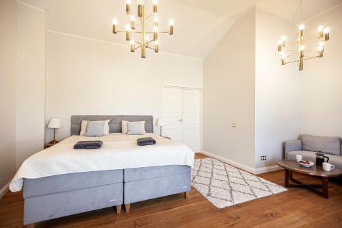 Habitación blanca con cama grande y lámpara de araña. en Luxury 2-floor apartment with sauna and balcony en Tallin