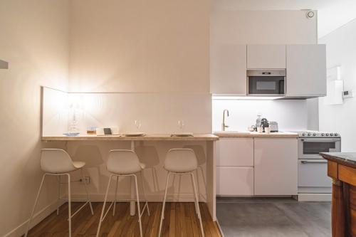 une cuisine avec des armoires blanches et des tabourets de bar dans l'établissement Aux Clefs des Sacres - Le Talleyrand, à Reims