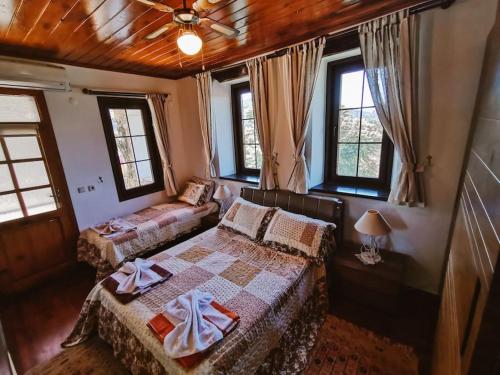 a bedroom with two beds in a room with windows at Orman İçinde Muhteşem Villa in Kayakoy
