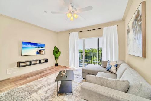 a living room with a couch and a ceiling fan at Bright Condo - 2BR with Pool & Hot Tub, near Disney! in Orlando