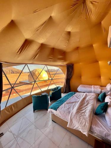 a bed in a room with a large window at Angelina Luxury Camp in Wadi Rum