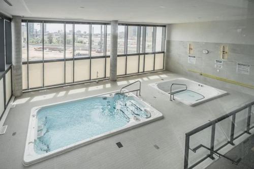 a large bath tub in a large room with windows at Brand New 1BR Condo - Balcony Amazing Views in Kitchener