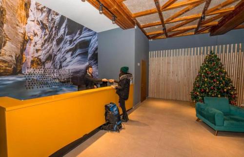 two people standing at a counter with a christmas tree at The Valley Residence & Spa SUITE 223 in Bakuriani