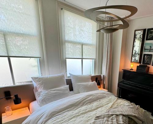 een slaapkamer met een bed met witte kussens en ramen bij WS77 Appartment in Leiden