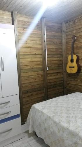 a bedroom with a bed and a guitar on the wall at Casa De Praia Galheta in Farol de Santa Marta