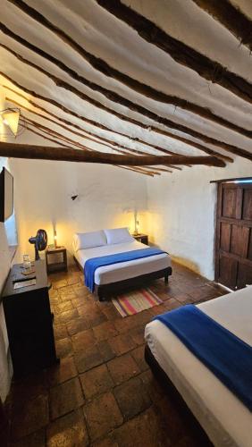 ein großes Schlafzimmer mit 2 Betten und einer Decke in der Unterkunft Casa Raisol in Barichara