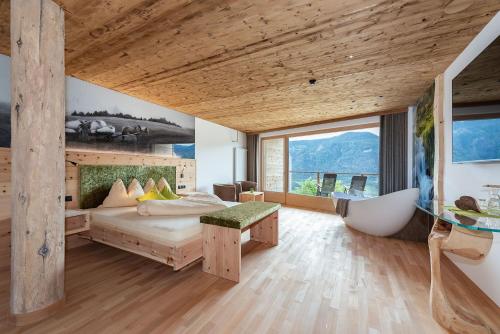 a bedroom with a bed and a tub and a large window at Moarlhof - Farm Nature Resort in Castelrotto