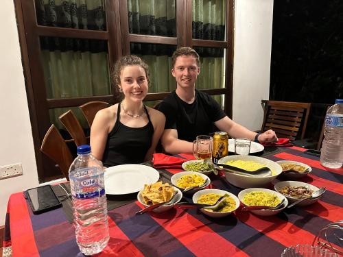 a man and woman sitting at a table with food at Sigiri Hibiscus Villa in Sigiriya
