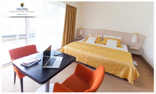 una camera d'albergo con letto e tavolo con computer portatile di Nicotel Pineto a Castellaneta Marina