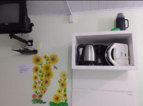 una cocina con una estantería con microondas y flores en la pared en Pousada Termas Piratuba en Piratuba