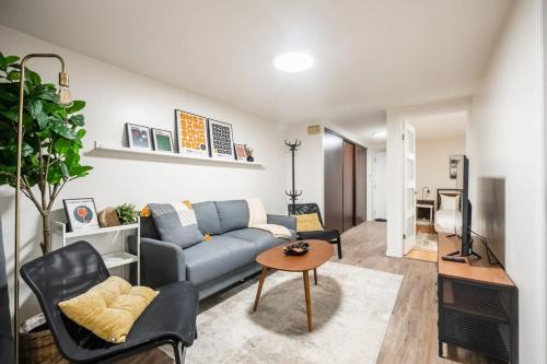 ein Wohnzimmer mit einem blauen Sofa und einem Tisch in der Unterkunft Modern 2BR Apt - Close to Trinity Bellwoods Park in Toronto