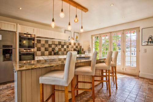 une cuisine avec un bar et des tabourets. dans l'établissement Villa la Cressonnière, à Deauville