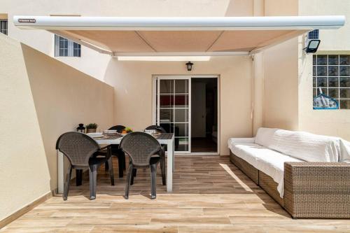 een patio met een tafel en stoelen en een bank bij Villa Aspen Gran Canaria in Arguineguín