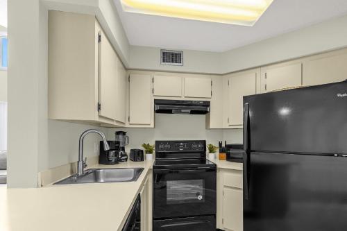 a kitchen with white cabinets and a black refrigerator at Modern Cozy 2BR Condo Near Disney in Orlando