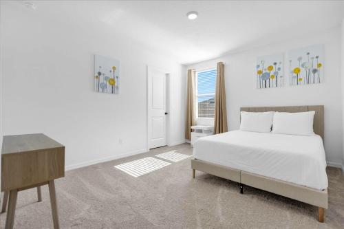 een witte slaapkamer met een bed en een bureau bij NEW BUILD - West Haven Lakefront Paradise in Davenport