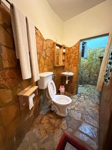 a stone bathroom with a toilet and a sink at Afro Smile Hotel and Guest House in Jinja