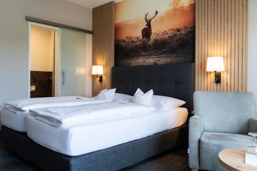 een slaapkamer met een groot wit bed en een stoel bij Sporthotel Zum Hohen Eimberg in Willingen