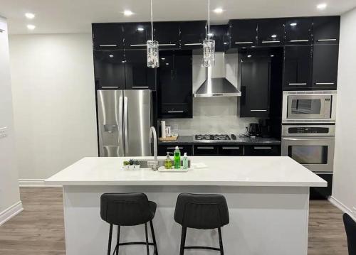 une cuisine avec un comptoir blanc et des armoires noires dans l'établissement Upscale 2BR Condo - Near Miliken District Park, à Markham