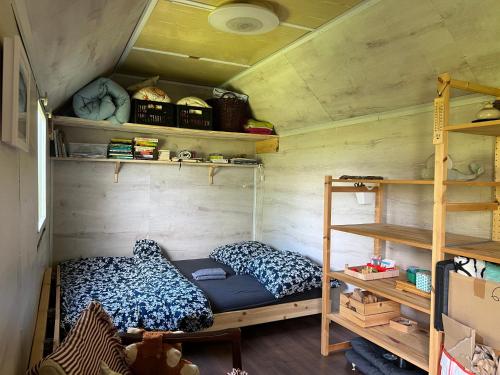 Una habitación con una cama y estanterías en una casa diminuta. en MECHový domeček nad pramenem, en Volary