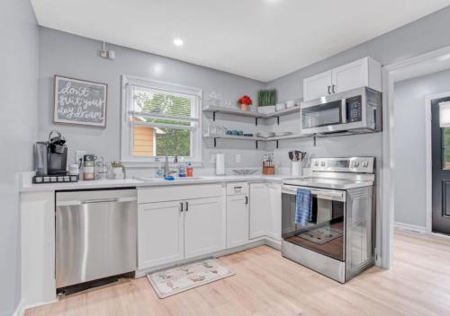 a kitchen with white cabinets and stainless steel appliances at Stylish Home Near Uptown, UNC, and More! in Charlotte