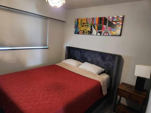a bedroom with a bed with a red bedspread at City Charm: Furnished 3-BR Retreat in Vancouver