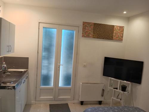 a kitchen with a sliding glass door and a tv at Studio de 14m2 dans une maison in Cagnes-sur-Mer