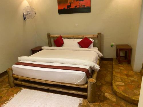 a bedroom with a large bed with red pillows at Afro Smile Hotel & Guest House in Jinja