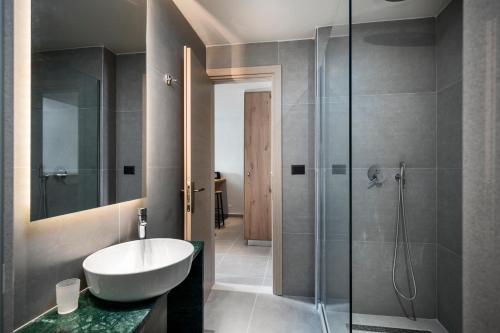 ein Bad mit einem Waschbecken und einer Glasdusche in der Unterkunft Loadstar Rooms & Suites in Kontokali