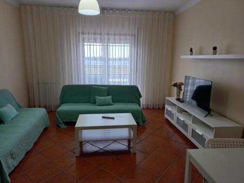 a living room with a green couch and a tv at Barra Atlântica Apartment 1 in Praia da Barra