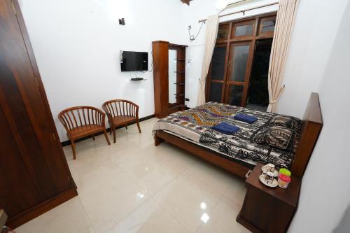 a bedroom with a bed and two chairs and a window at Jaruv Royal Residencies in Divulpitiya