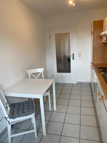 a kitchen with a white table and chairs and a door at Ferienhof Kröger in Bielefeld