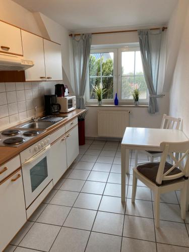 a kitchen with white cabinets and a table and a table and a microwave at Ferienhof Kröger in Bielefeld