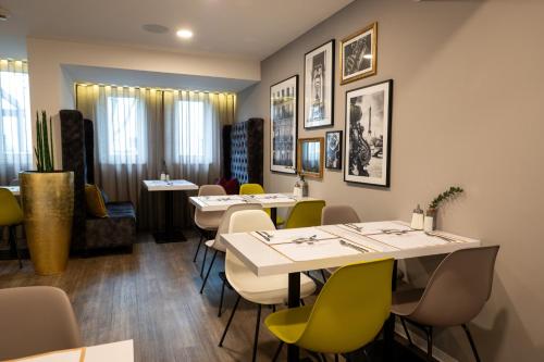a restaurant with tables and chairs and pictures on the walls at V Boutique Hotel Böblingen in Böblingen