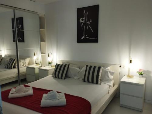 a bedroom with a large white bed with mirrors at The LOFT IBIZA in Ibiza Town