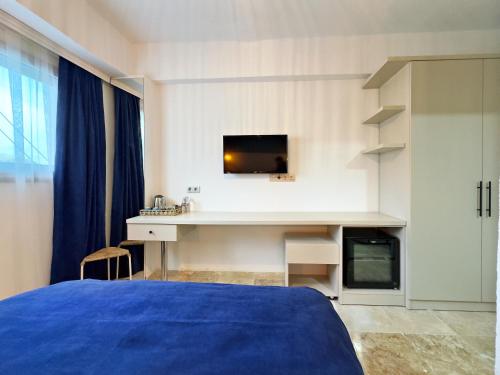 a bedroom with a bed and a desk with a tv at Nese Pension in Bodrum City