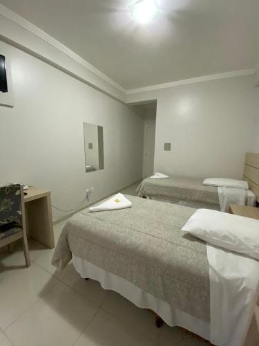 a hotel room with two beds and a desk at North Hotel - Aeroporto in Chapecó