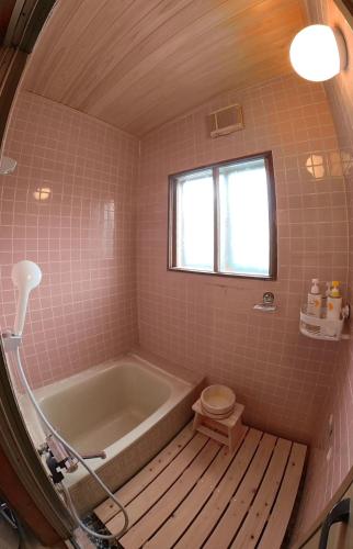 a bathroom with a tub and a toilet and a window at 大人数の家族旅行に！BBQ(夏)/雪遊び(冬)/しゃぶしゃぶの鍋/カラオケ/Switch/映画も！ in Kami-furano
