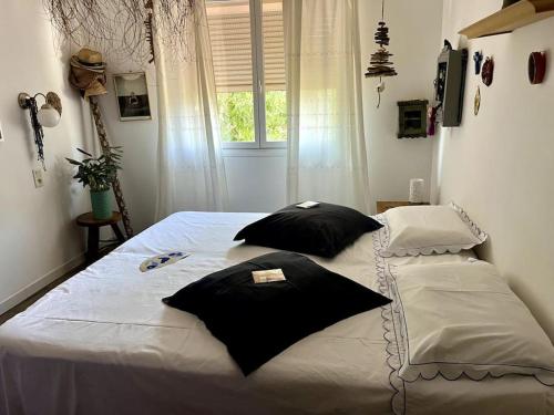 a bed with black pillows on it in a bedroom at La campagne a la mer sur la cote bleue in Martigues