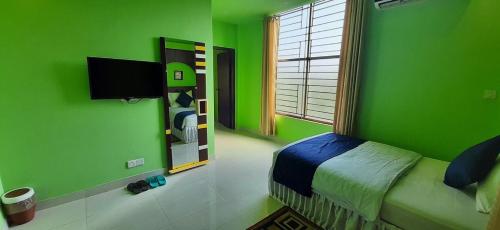 Dormitorio verde con cama y TV en D'more Sreemangal Hotel & Resort en Sreemangal