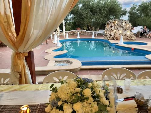 un tavolo con fiori accanto a una piscina di One bedroom apartement with shared pool enclosed garden and wifi at Crispiano a Crispiano