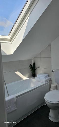 a white bathroom with a toilet and a skylight at Gästehaus Orchidee in Hoya