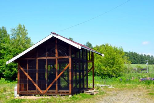 a small wooden building with a metal roof at 大人数の家族旅行に！BBQ(夏)/雪遊び(冬)/しゃぶしゃぶの鍋/カラオケ/Switch/映画も！ in Kami-furano