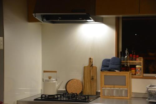 a kitchen with a stove with a light above it at 大人数の家族旅行に！BBQ(夏)/雪遊び(冬)/しゃぶしゃぶの鍋/カラオケ/Switch/映画も！ in Kami-furano