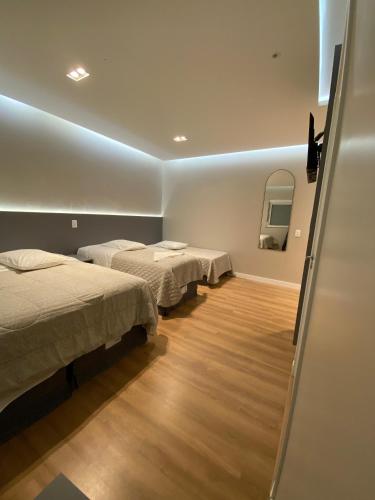 a room with two beds and a room with a mirror at North Hotel - Aeroporto in Chapecó