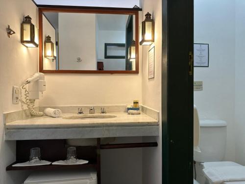 a bathroom with a sink and a mirror and a toilet at Pousada do Príncipe in Paraty