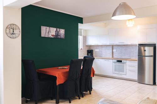 a kitchen with a table with black chairs and a green wall at Villa Infinity View Athens Riviera in Anavissos