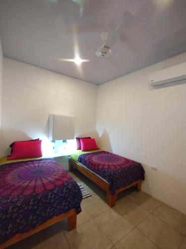 two beds in a room with red and green pillows at Casajungla Hostel in Jacó