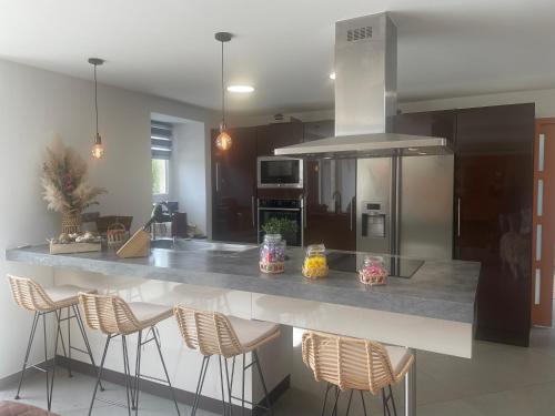 une cuisine avec un grand comptoir et des tabourets. dans l'établissement Maison de charme, à Yvetot Bocage