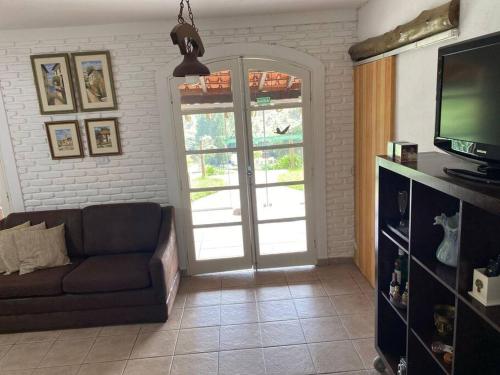 ein Wohnzimmer mit Sofa und Fernseher in der Unterkunft Sítio Vale da Colina-Nazaré Paulista - 8 pessoas in Nazaré Paulista