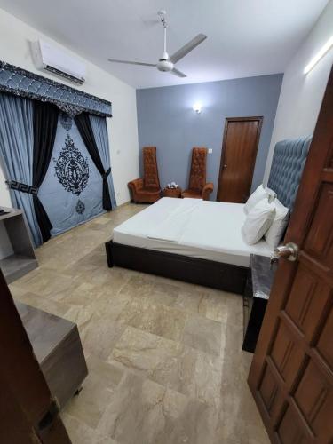 1 dormitorio con 1 cama grande y 2 sillas en Blue diamond guest house en Karachi